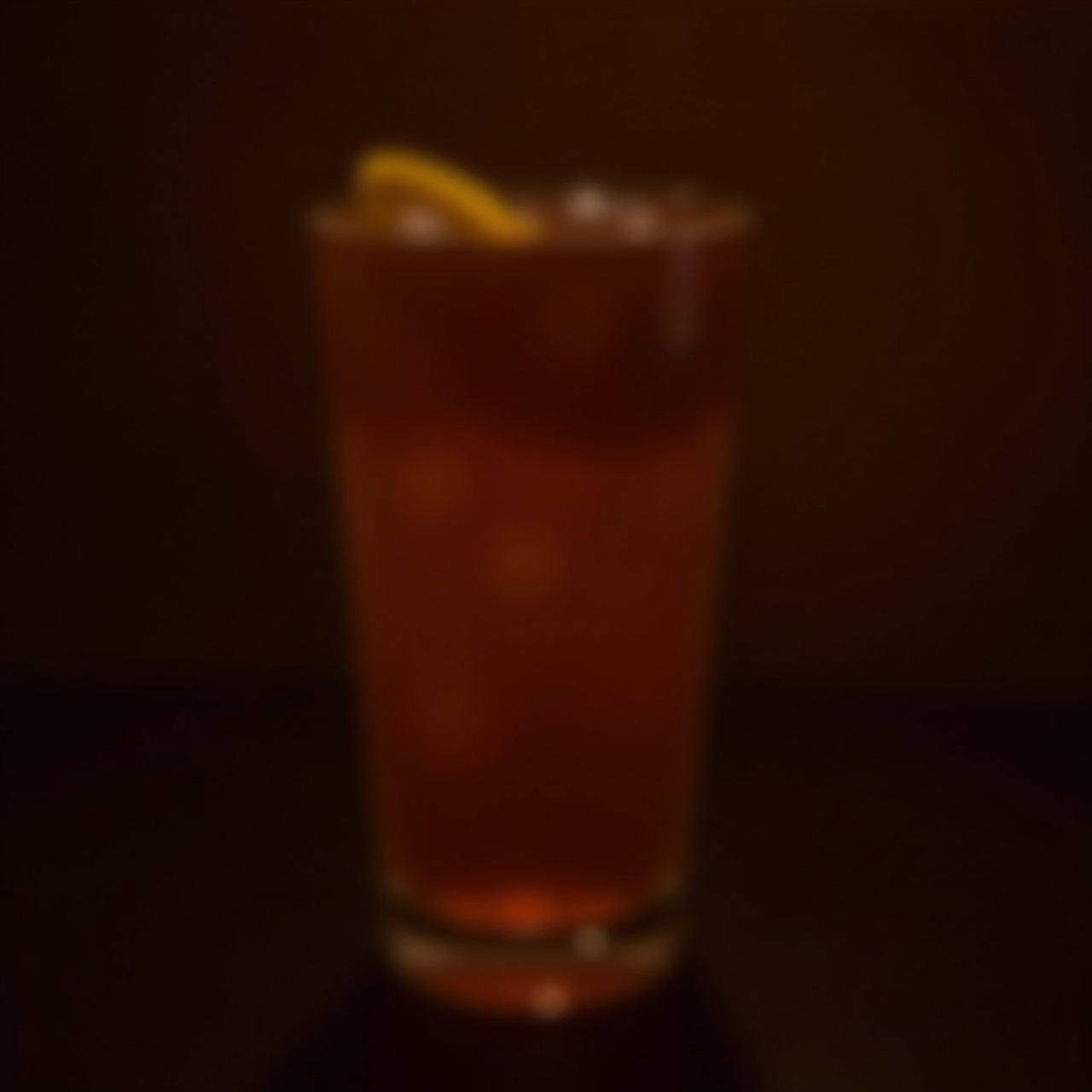 an amber cocktail on a dark bar